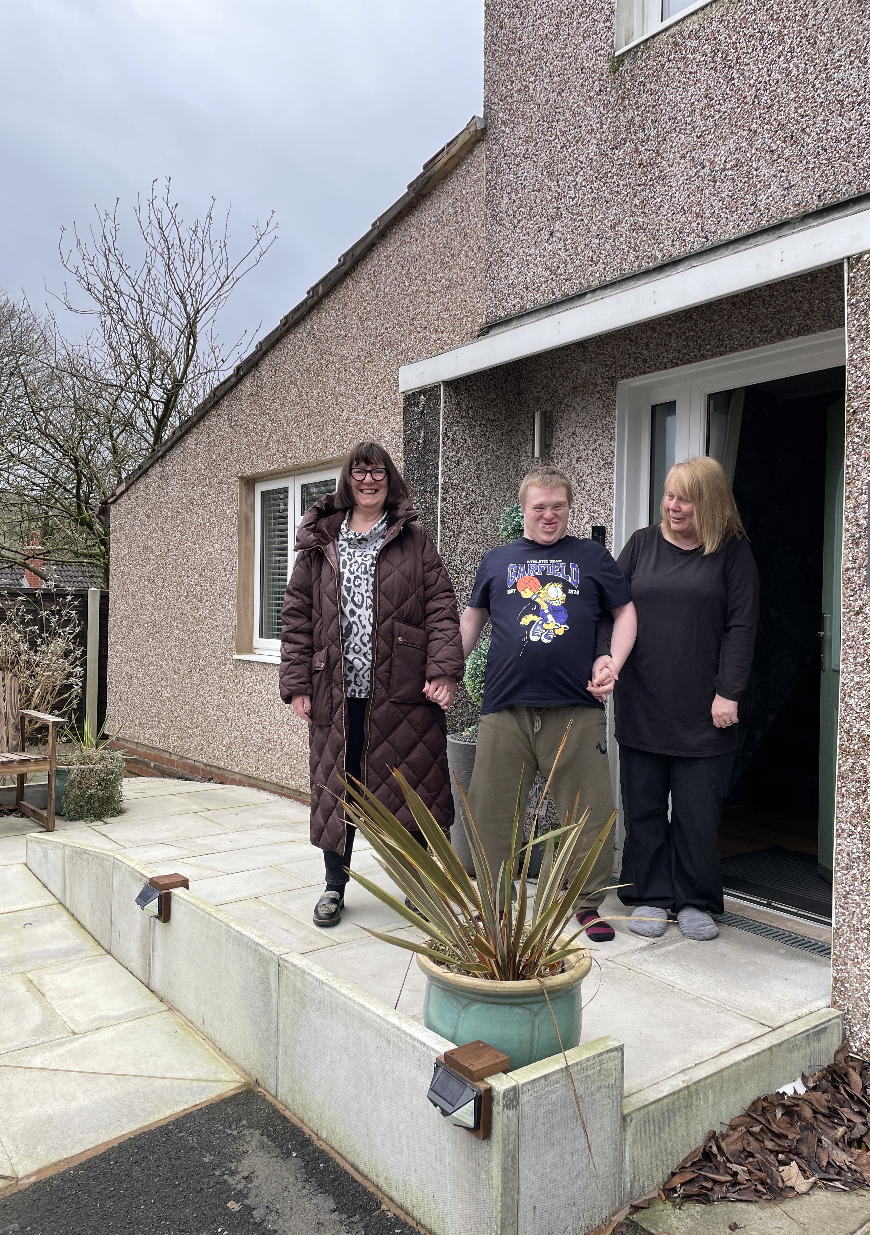 cllr Ashworth holding hands with christopher & his mum christine outside their home