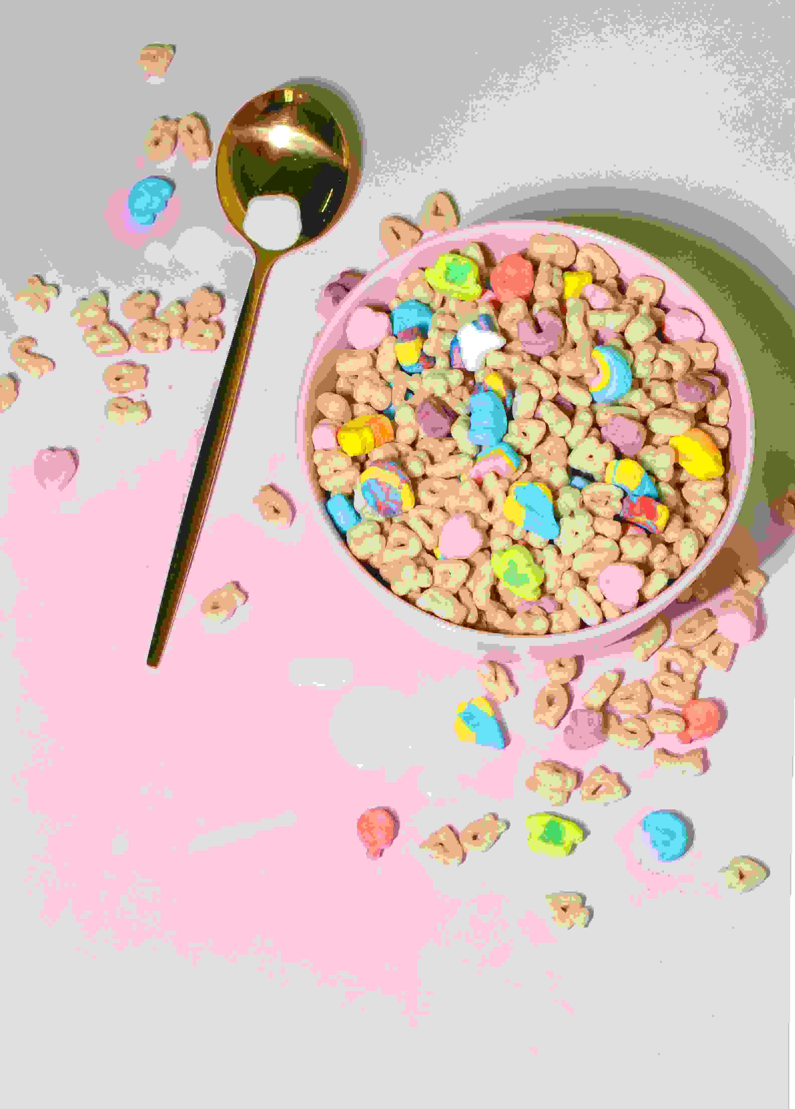 colourful bowl of cereal with spilt milk and a spoon